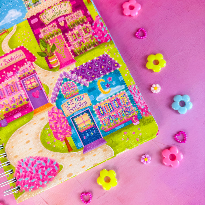 Close up of Bookshop Avenue spiral notebook on a pink backdrop