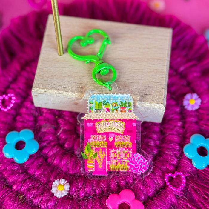 Botanical bookshop keychain against a pink backdrop