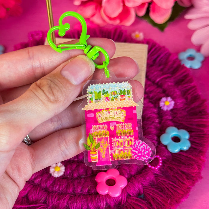 Botanical bookshop keychain against a pink backdrop