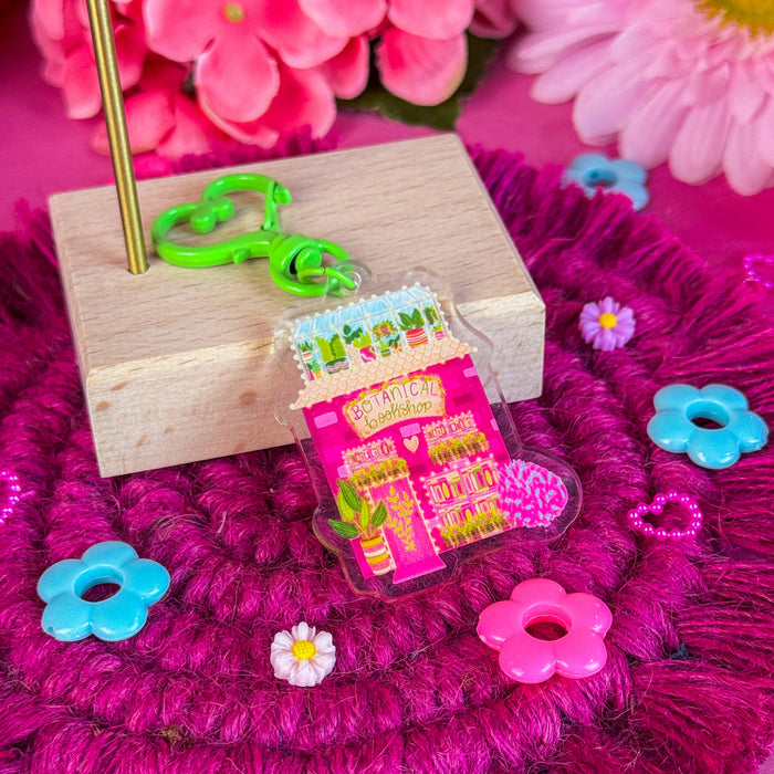 Botanical bookshop keychain against a pink backdrop