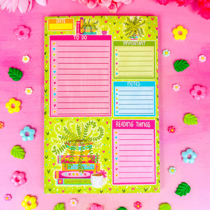 A notepad with sections for a to do list, important items, notes, and reading things. Featuring a green plant in the lower left corner and spring themed books and hearts around the border.
