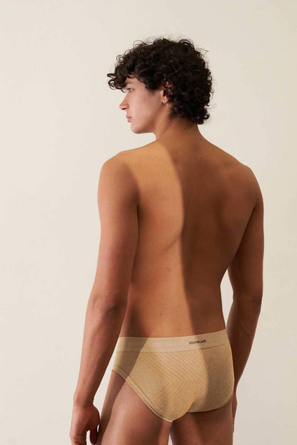 Model wearing a tailored organic cotton brief in Sand with Orange Cross, showcasing comfort and minimal design.