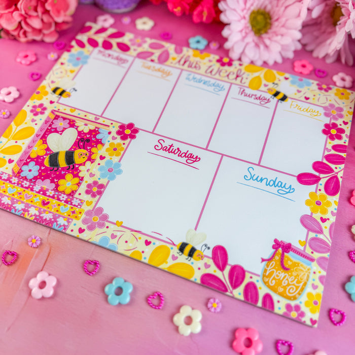 Floral-themed weekly planner on a pink surface with flowers around