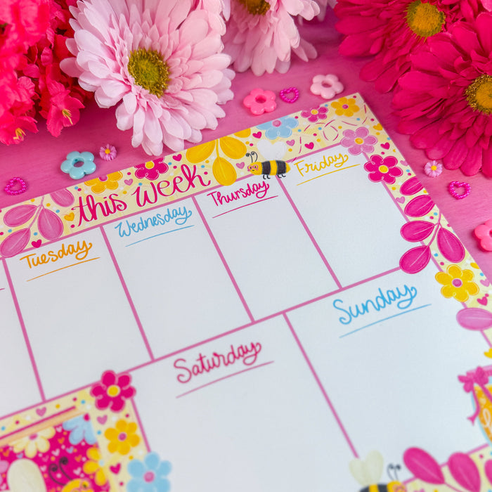 Weekly planner with bee design on a pink background with flowers around