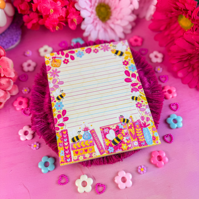 Colorful notepad with decorative border on a pink background with flowers