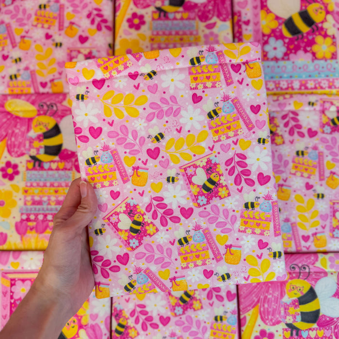 Colorful book sleeve with bee and heart patterns, held by a hand.