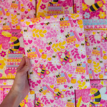 Colorful book sleeve with bee and heart patterns, held by a hand.