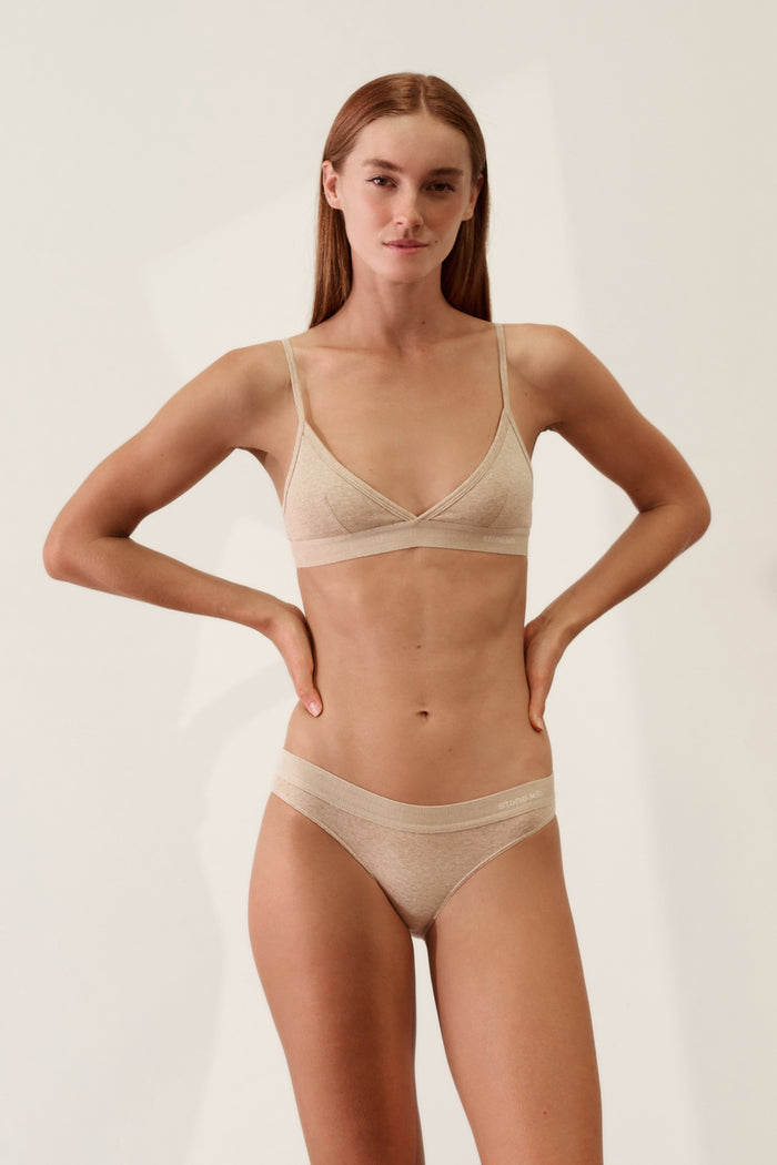 Model wearing Cheeky in Organic Cotton Rib - Sand bikini, showcasing soft fabric and comfortable fit.