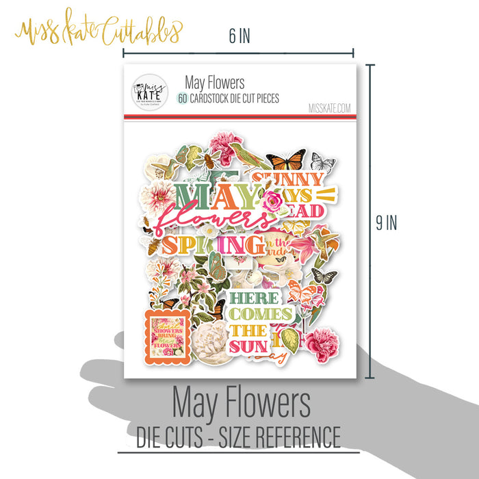 May Flowers Die Cuts, size guide shown in hand for scale, showing pre-cut scrapbook embellishments for layouts, handmade cards, journals, mini albums, memory pages, and layered paper crafts. Buyer theme: Spring Floral Die Cuts & Garden Ephemera. May Flowers die cuts with flowers, butterflies, bees, birds, hummingbirds, seed packets, leaves and cheerful spring phrases. Color palette includes Rose pink, coral, blush, sage green, mint, yellow, orange, cream and charcoal