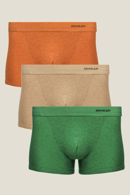 Three pairs of Stone.kin men's boxer briefs in orange, beige, and green, stacked vertically against a light beige background.