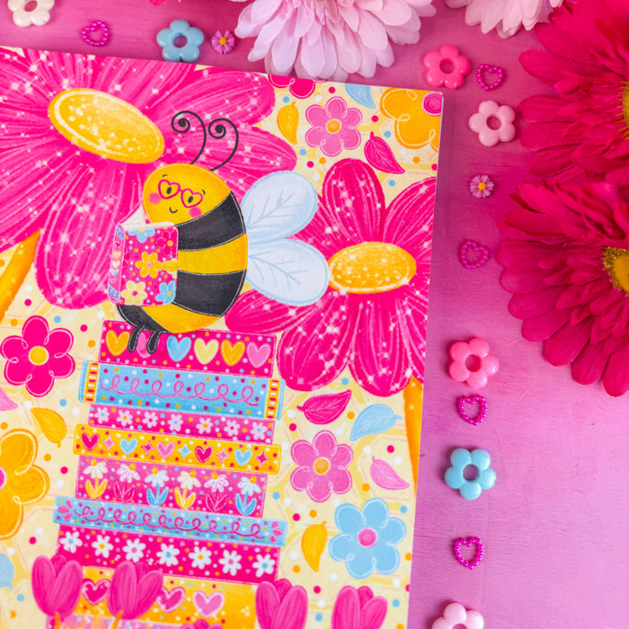 Colorful notebook with a bee illustration surrounded by pink flowers