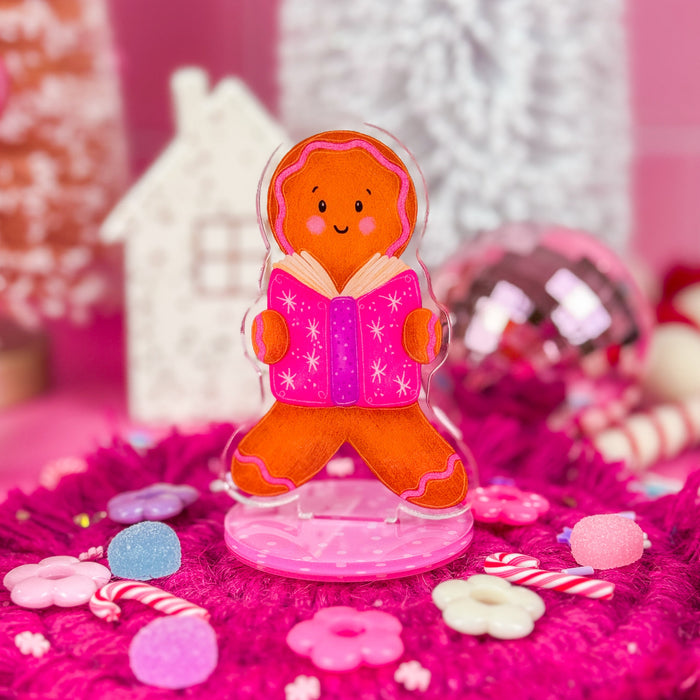 A clear acrylic stand featuring an illustration of a gingerbrea holding an open book.