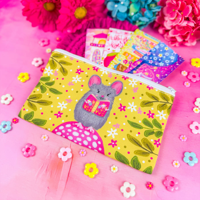 A white zippered fabric pouch. The pattern on the pouch features a mouse holding a pink book against a chartreuse background decorated with pink and white flowers and green leaves.
