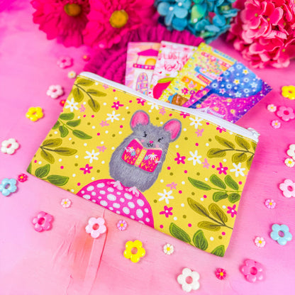 A white zippered fabric pouch. The pattern on the pouch features a mouse holding a pink book against a chartreuse background decorated with pink and white flowers and green leaves.