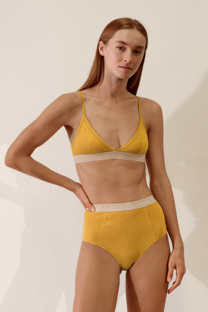 Model wearing a Scoop Back Bralette in Organic Cotton Rib - Mustard / Sand, featuring soft fabric and a stylish design.