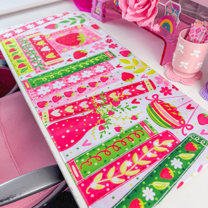 Strawberry bookshelf desk mat on a desk with pink decor